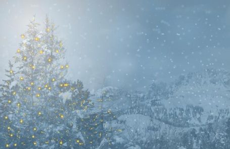Winterlandschaft mit geschmücktem Baum und Schneefall unter einem blauen Himmel.