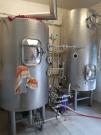 Zwei große, silberne Brautanks mit Rohren und Ventilen in einem Brauerei-Raum.