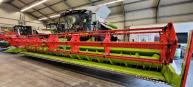 Große Feldmaschine mit rotem und grünem Design, in einer Lagerhalle abgestellt.